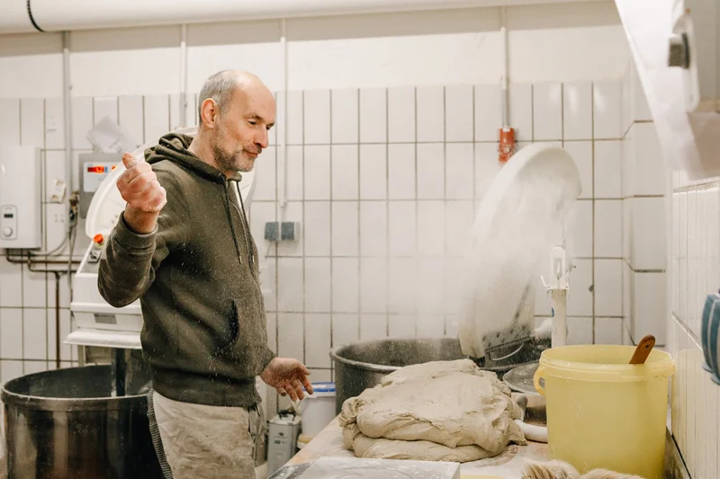 Ein Mann, wie er Teig zubereitet. Klick führt zu Großansicht.