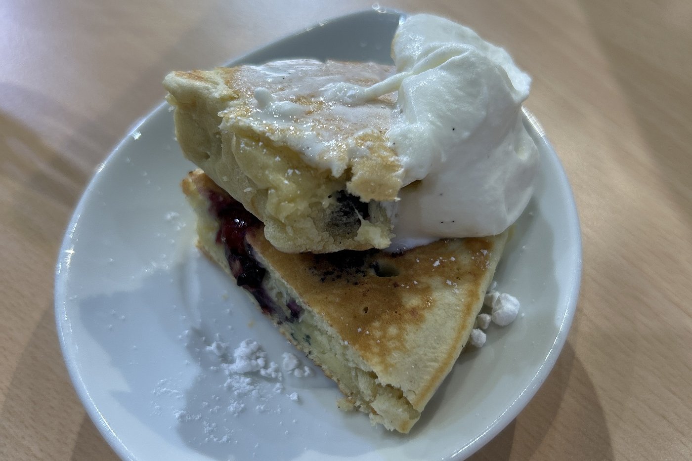 Blaubeerpfannkuchen mit Vanillesahne auf einem Teller angerichtet. Foto: BLE