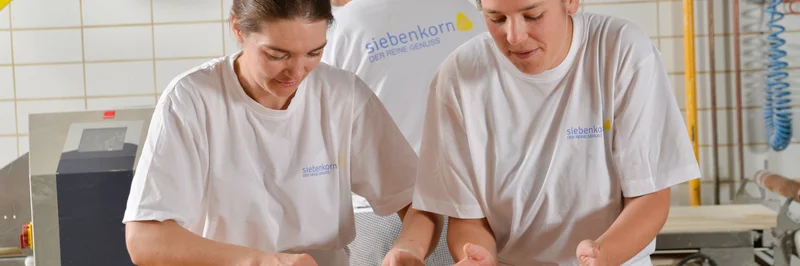 Zwei Frauen, die in einer Backstube Gebäck zubereiten.