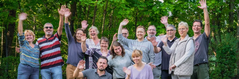 Gruppe von Menschen winkt in die Kamera.