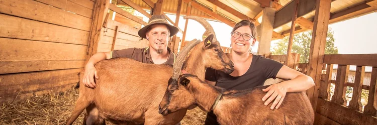 Mann und Frau mit Ziegen im Stall
