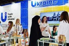 Frauen an einem Messestand. Über dem Messestand steht die Aufschrift "Ukraine". Klick führt zu Großansicht.
