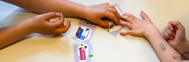Kinderhände ordnen Kärtchen zur Wertschöpfungskette von Obst.