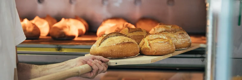 Brot wird aus einem Backofen geholt.