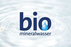 Das Wörtchen "bio" in blau auf einem Wasserhintergrund. Im Buchstaben "O" des Wortes "bio" befindet sich ein Wassertropfen. Darunter steht "Mineralwasser" in blauer Schrift. Klick führt zu Großansicht.