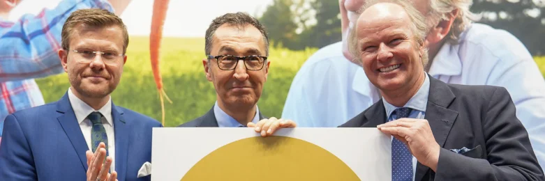 Stefan Hipp, Cem Özdemir und Marcus König halten das Bio-Logo in Gold