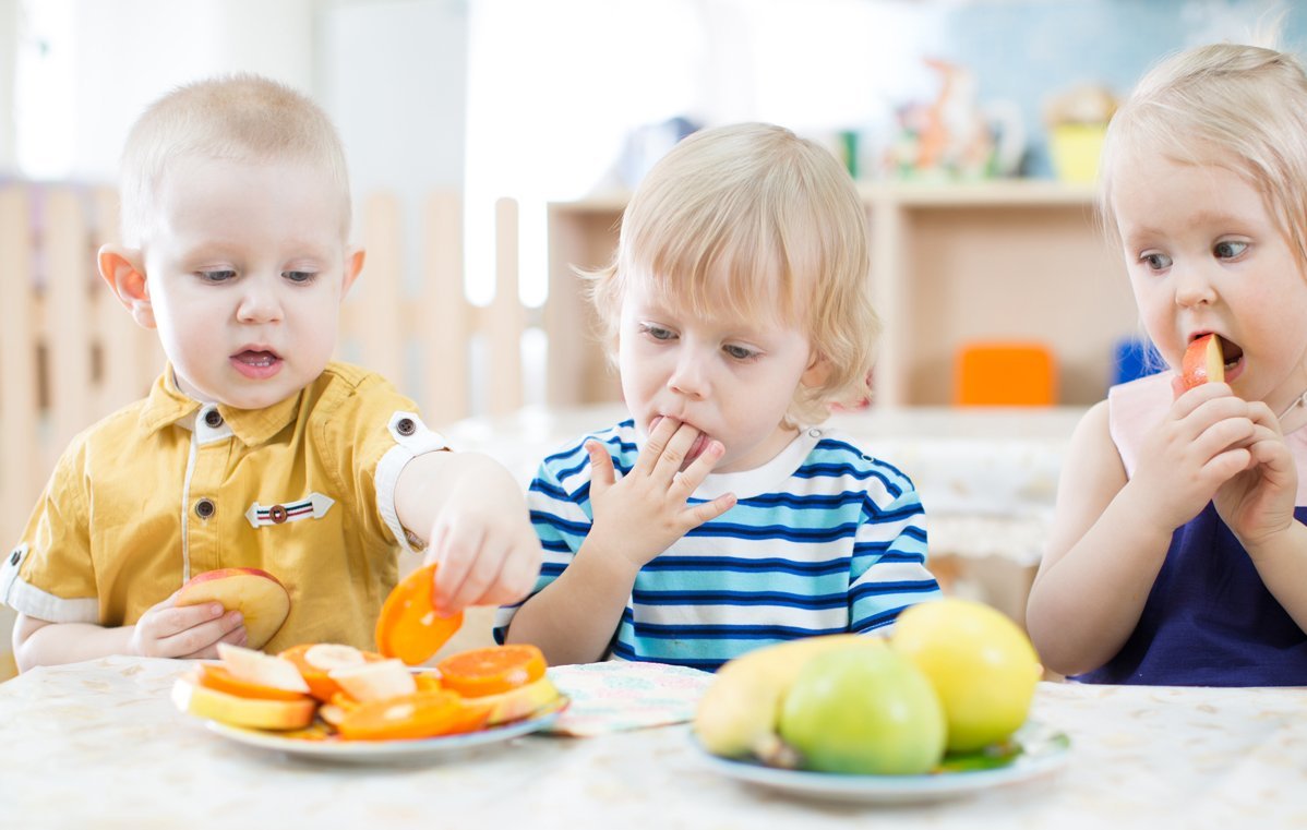 Drei Kinder essen Obst.