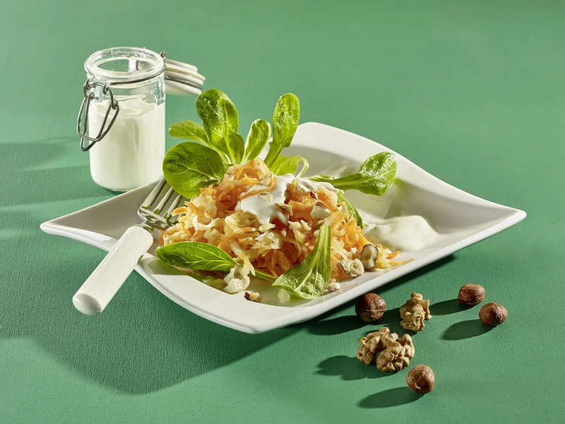 Rüben-Apfelsalat mit Nüssen auf Teller angerichtet.