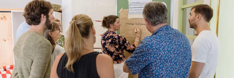 Gruppe von Menschen um eine Plakatwand