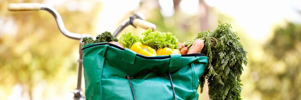 Tasche voller Gemüse auf dem Gepäckträger eines Fahrrads.