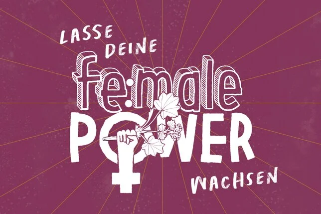 Beerenfarbiger Hintergrund. In weißer Schrift steht dort "Lasse deine female Power wachsen". Im "O" von Power ist eine Hand zu sehen mit Kräutern in der Hand. Das O mit der Hand wird zum Zeichen für Frauen. Klick führt zu Großansicht.