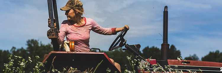 Frau sitzt auf Traktor.