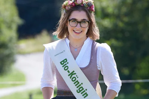 Eine Frau im Dirndl mit einer Scherpe um, auf der Bayerische Bio-Königin steht. Klick führt zu Großansicht.