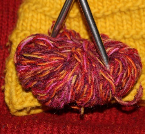 Rote und Gelbe Biowolle mit Stricknadeln. Klick führt zu Großansicht im neuen Fenster.