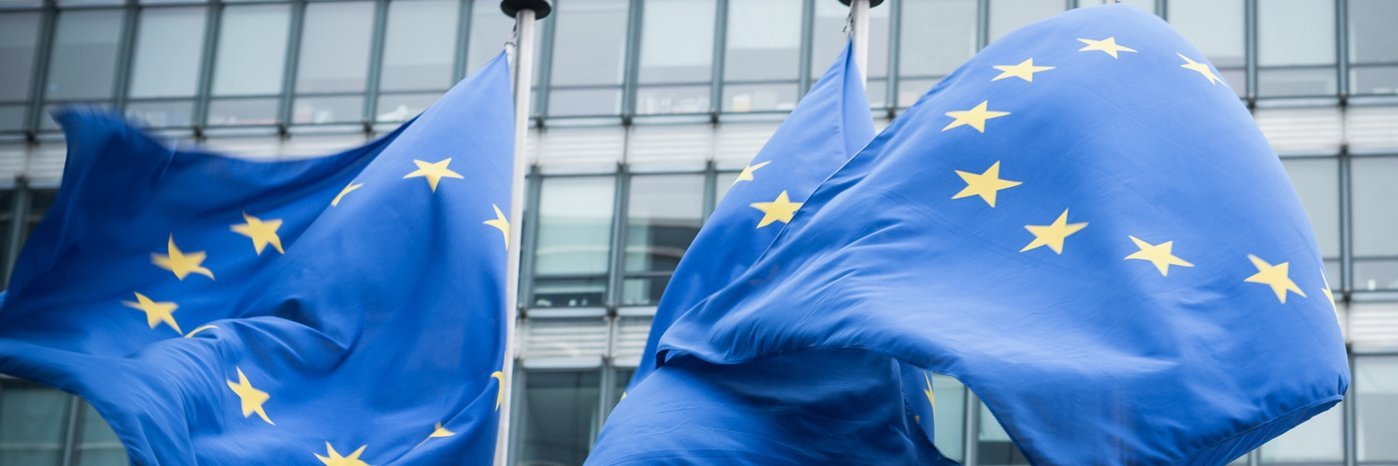 Zwei EU-Flaggen wehen vor einem Gebäude.