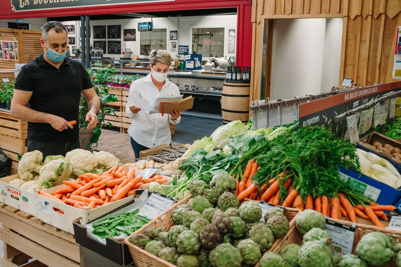 Mann und Frau stehen in der Gemüseabteilung eines Supermarktes