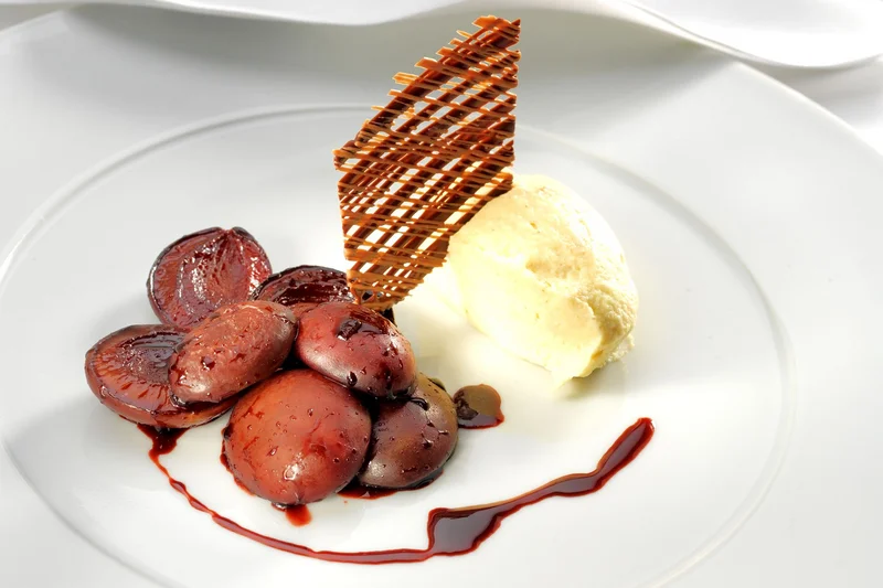 Weißes Schokoladen-Lebkuchen-Mousse mit Rotweinzwetschgen auf Teller angerichtet. Foto: Käflein