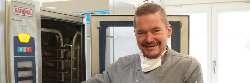 Mann holt Kartoffeln aus dem Ofen.