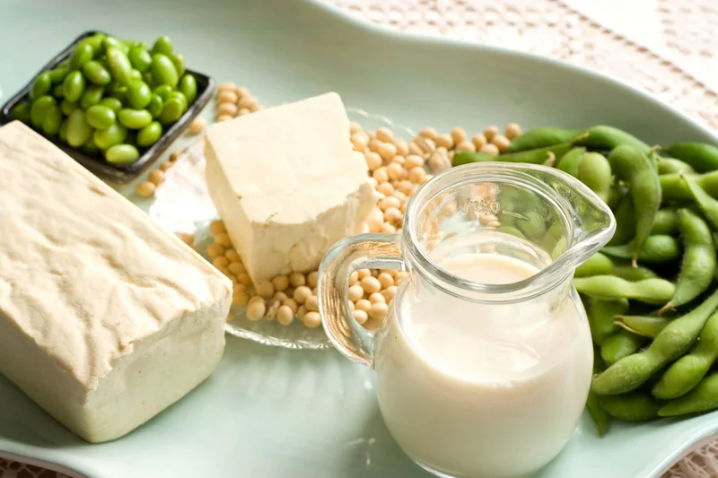 Tofu, Sojabohnen und ein Glas Milch auf einem Teller.