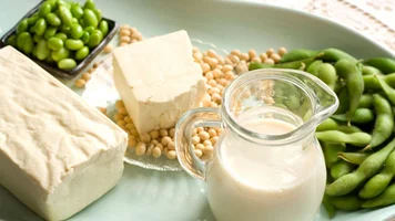 Tofu, Sojabohnen und ein Glas Milch auf einem Teller.