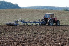 Traktor auf Feld bei der Bodenbearbeitung. Klick führt zu Großansicht.