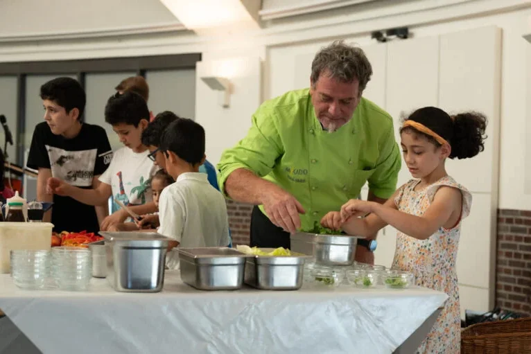 Koch mit Kindern im Kochkurs.