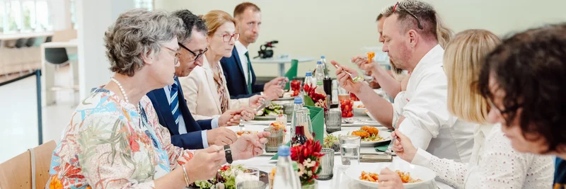 Cem Özdemir und andere sitzen an einem Tisch und essen