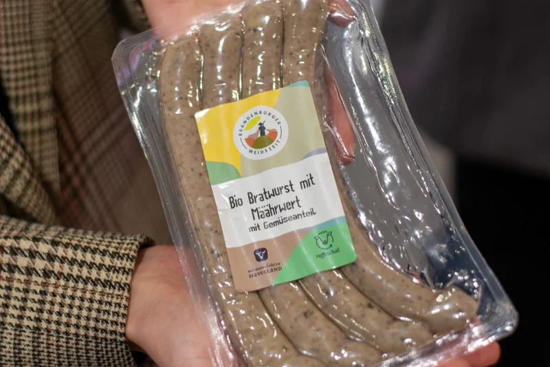 Hände, die eine Packung Wurst in der Hand halten.