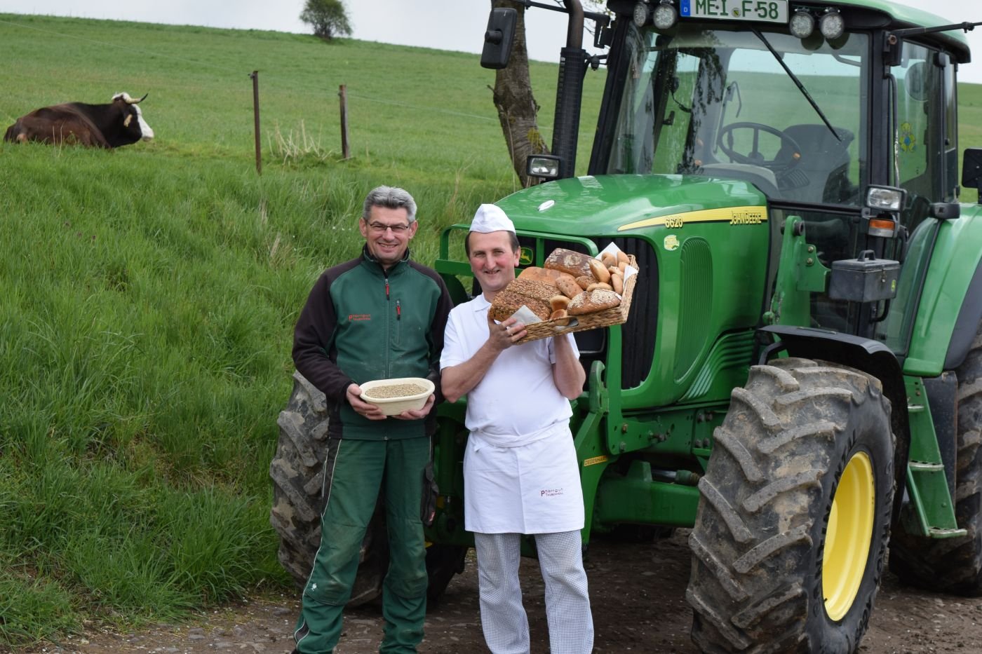 Männer mit Backwaren vor Traktor