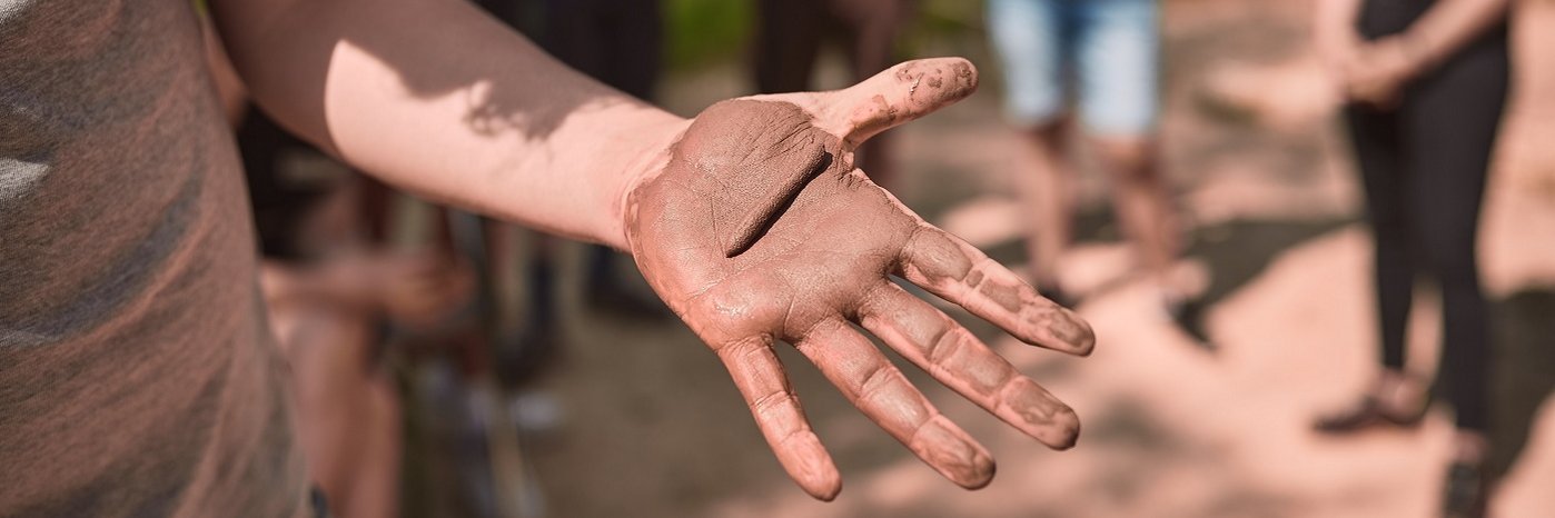 Eine Hand mit Lehm in der Hand.