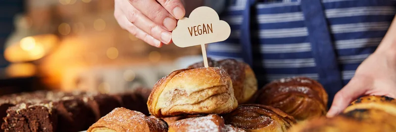 Schild "vegan" wird in vegane Backwaren gesteckt
