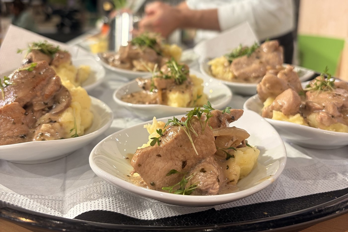 Gebratener Schweinenacken mit cremiger Polenta und Knoblauch-Mandelöl angerichtet auf einem Teller.