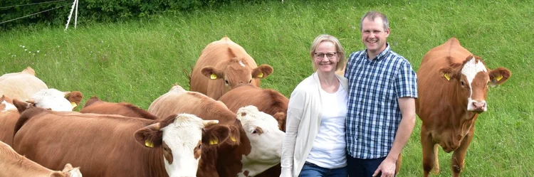 Mann und Frau auf Weide neben Kühen