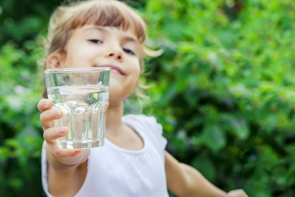 Kind hält Wasserglas in die Kamera, Klick führt zu Großansicht in neuem Fenster, Schließen per ESC.