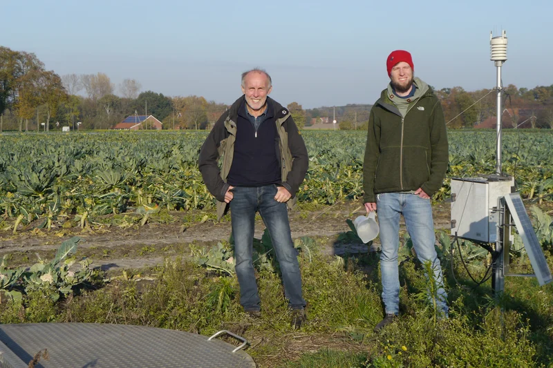 Zwei Männer vor einem Feld. Klick führt zu Großansicht in neuem Fenster.