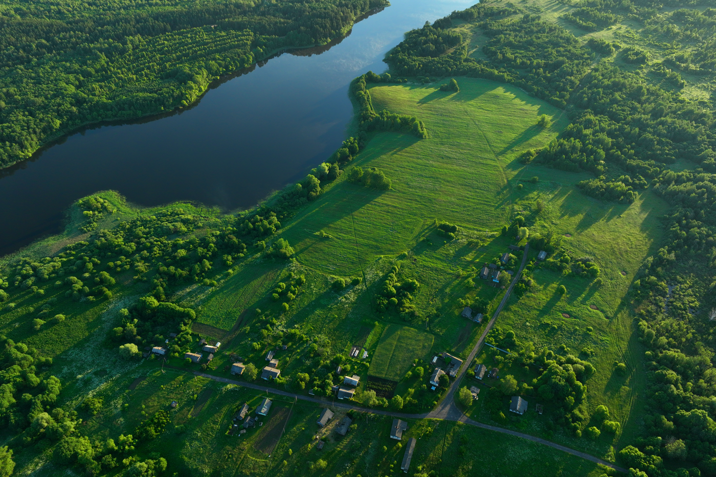 Luftaufnahme eines Sees, an dessen Ufer Wald und Grünflächen sind