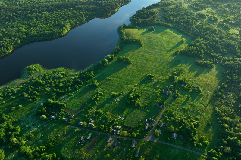 Luftaufnahme eines Sees, an dessen Ufer Wald und Grünflächen sind