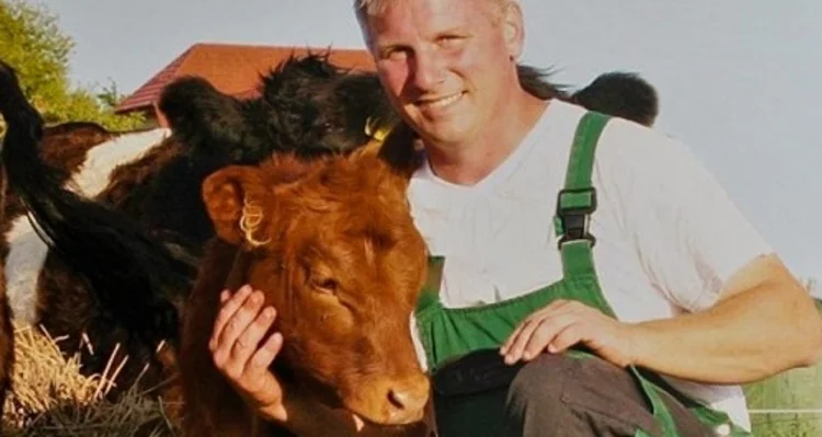 Landwirt mit braunem Kalb. Klick führt zu Großansicht im neuen Fenster.