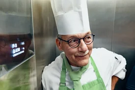 Ein Koch steht in einer Großküche vor einem Kombidämpfer und blickt zur Seite.
