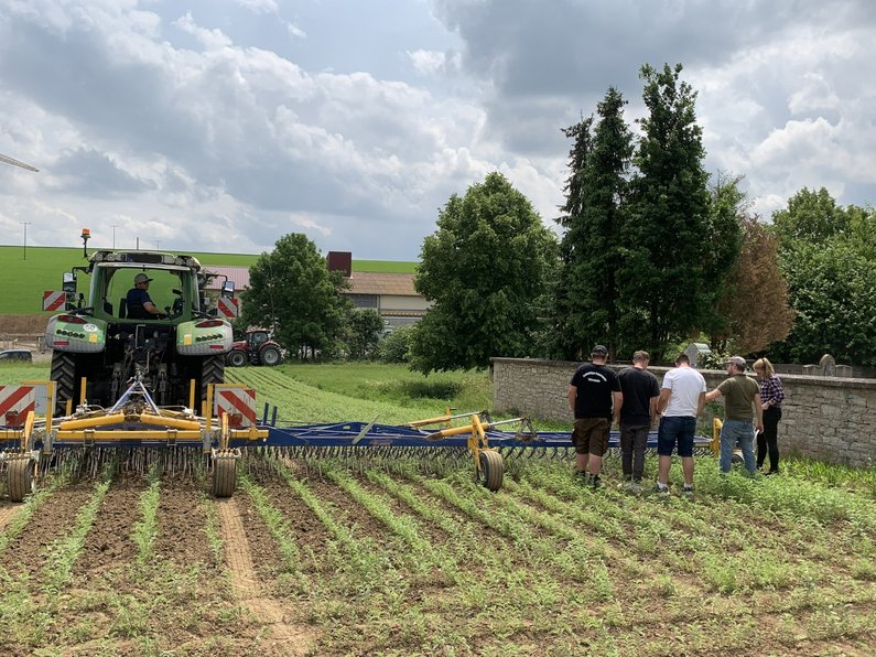 Auszubildende und Landmaschine auf einem Feld.