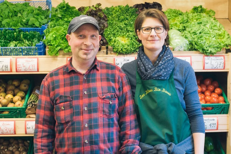 Mann und Frau vor Gemüseregalen