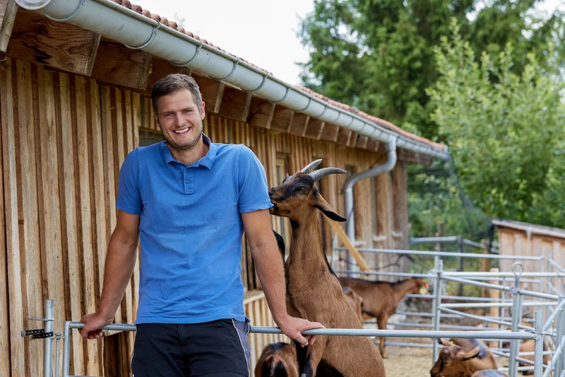 Bio-Milchziegen im Auslauf mit Landwirt Johannes Egger. Klick führt zu Großansicht.