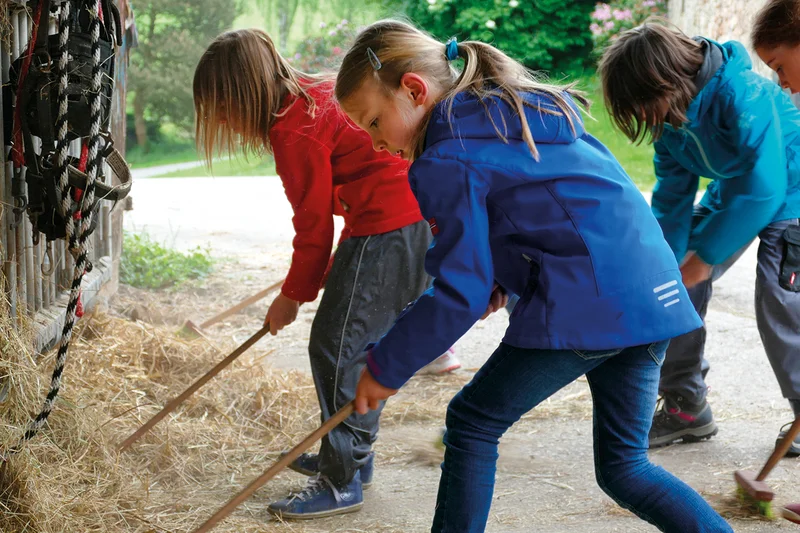 Kinder fegen Heu
