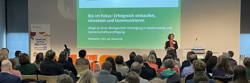 Moderatorin Claudia Zilz auf der Bio-AHV-Fachtagung und Publikum im Vordergrund.