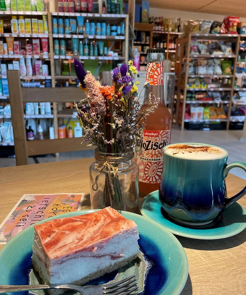 Hofladen mit Café; im Vordergrund ein Tisch mit Kuchen und Kaffee