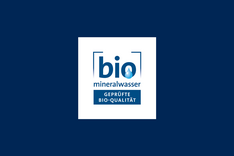 Logo der Qualitätsgemeinschaft Bio-Mineralwasser. In blauer Schrift von einem blauen Rahmen umgeben steht dort in groß "bio" und "mineralwasser", darunter "geprüfte Bio-Qualität". Das Logo ist auf dunkelblauem Hintergrund. Klick fürt zu Großansicht.