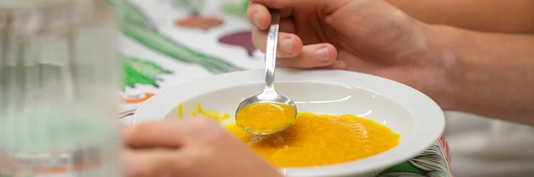 Teller mit Suppe und Löffel.