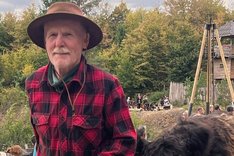 Mann mit Hut und einem Kalb an einer Leine. Klick führt zu Großansicht.