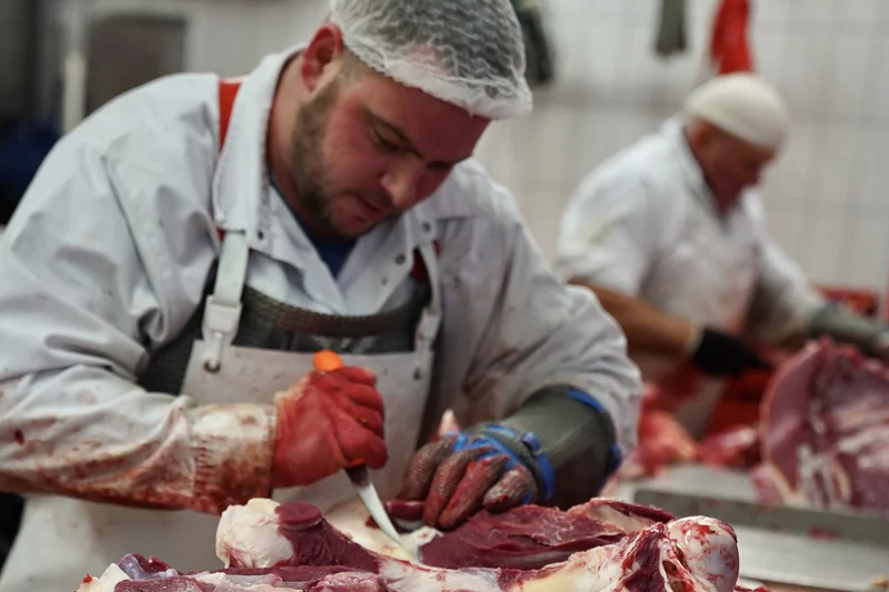 Ein Mann beim Zerlegen von Fleisch. Klick führt zu Großansicht.