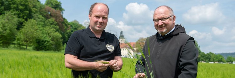 Zwei Männer stehen auf einem Feld vor dem Kloster